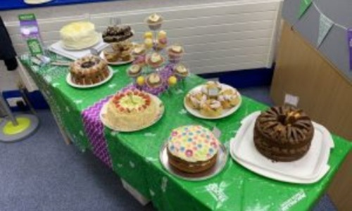 A bake sale stand with various cakes and cupcakes on it.