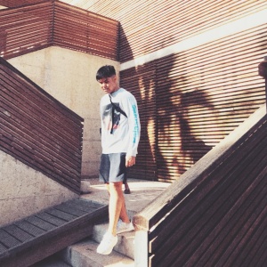 Man dressed in summer clothing walking down a set of stairs.