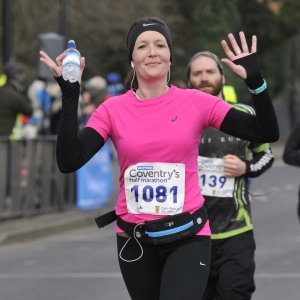 Lady waving at supporters whilst running the Coventry half marathon.