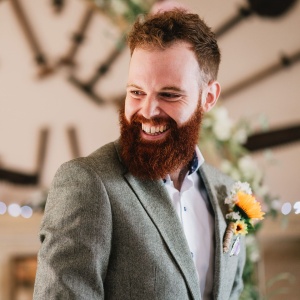 A groom wearing a suit smiling on his wedding day.