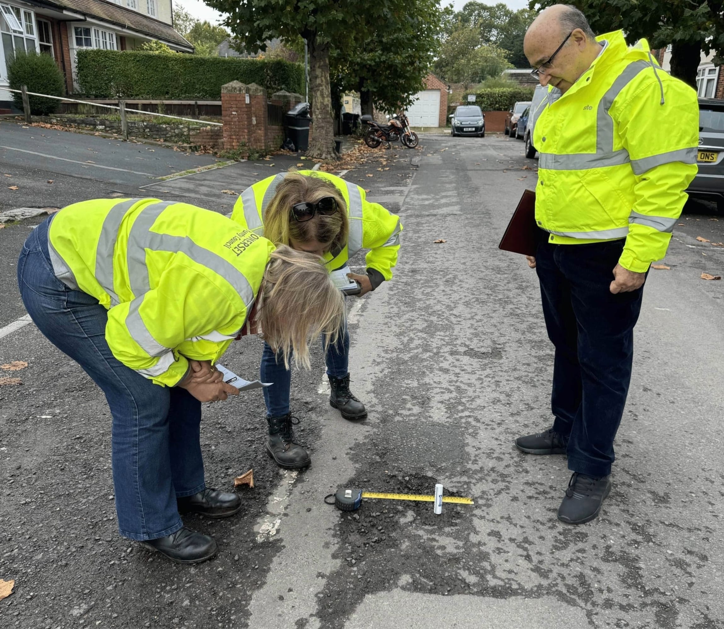 A man carrying out a road safety audit where he is measuring a pothole.
