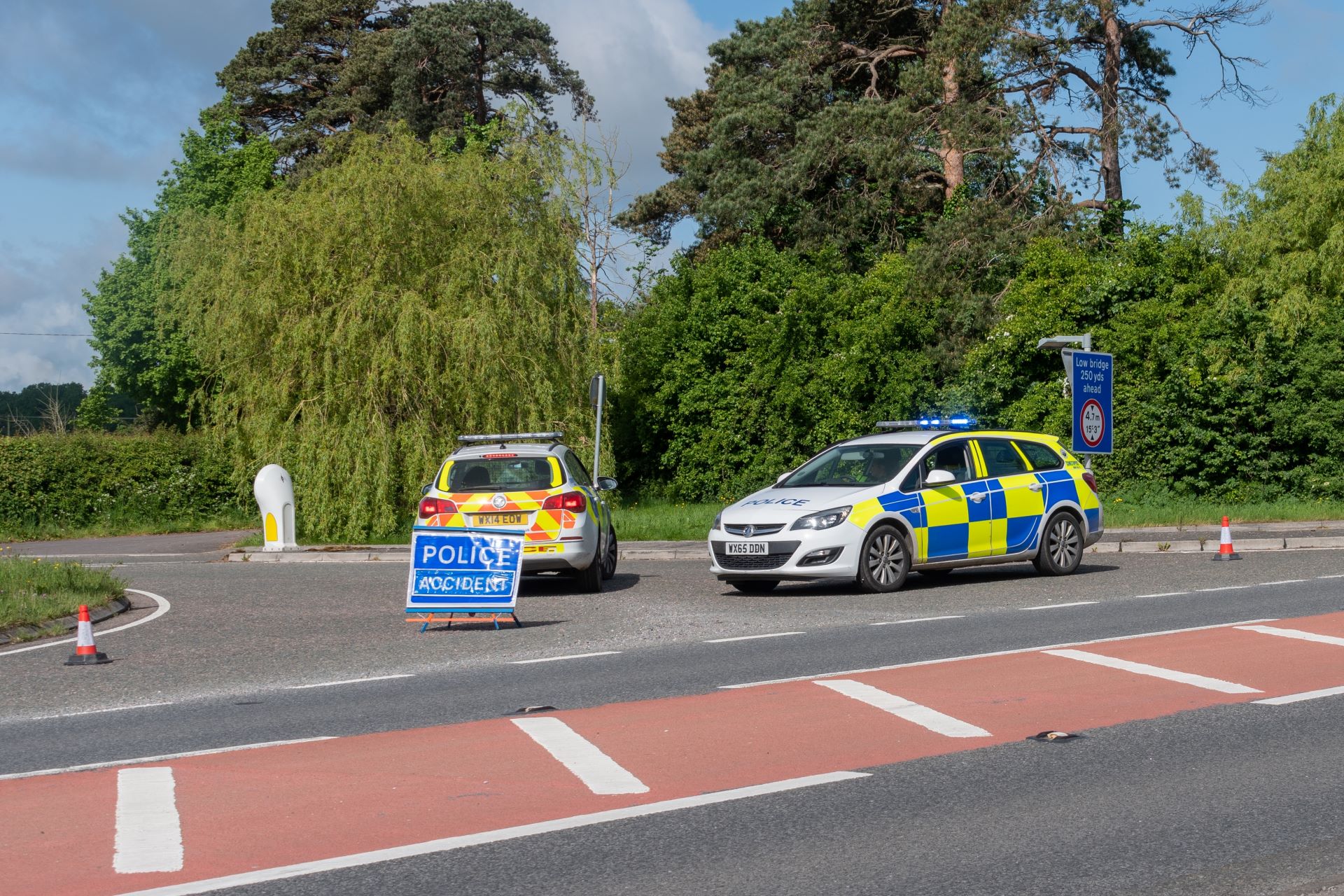 Two police cars that have closed off a road due to a collision.