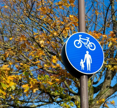 a cycle lane and pedestrian crossing warning sign on a lamp post