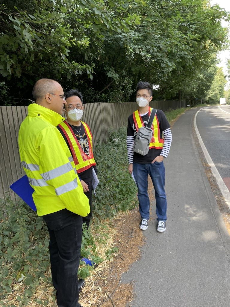 Three people in yellow vests talking to a man on the side of the road.
