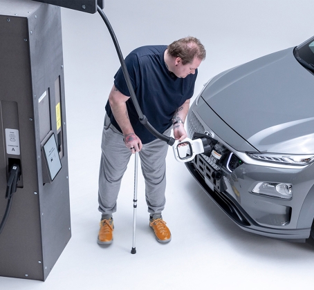 Disabled man charging an electric car with an EV charger.