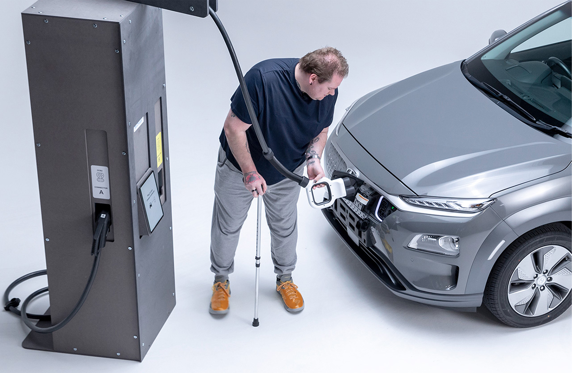 Disabled man charging an electric car with an EV charger.