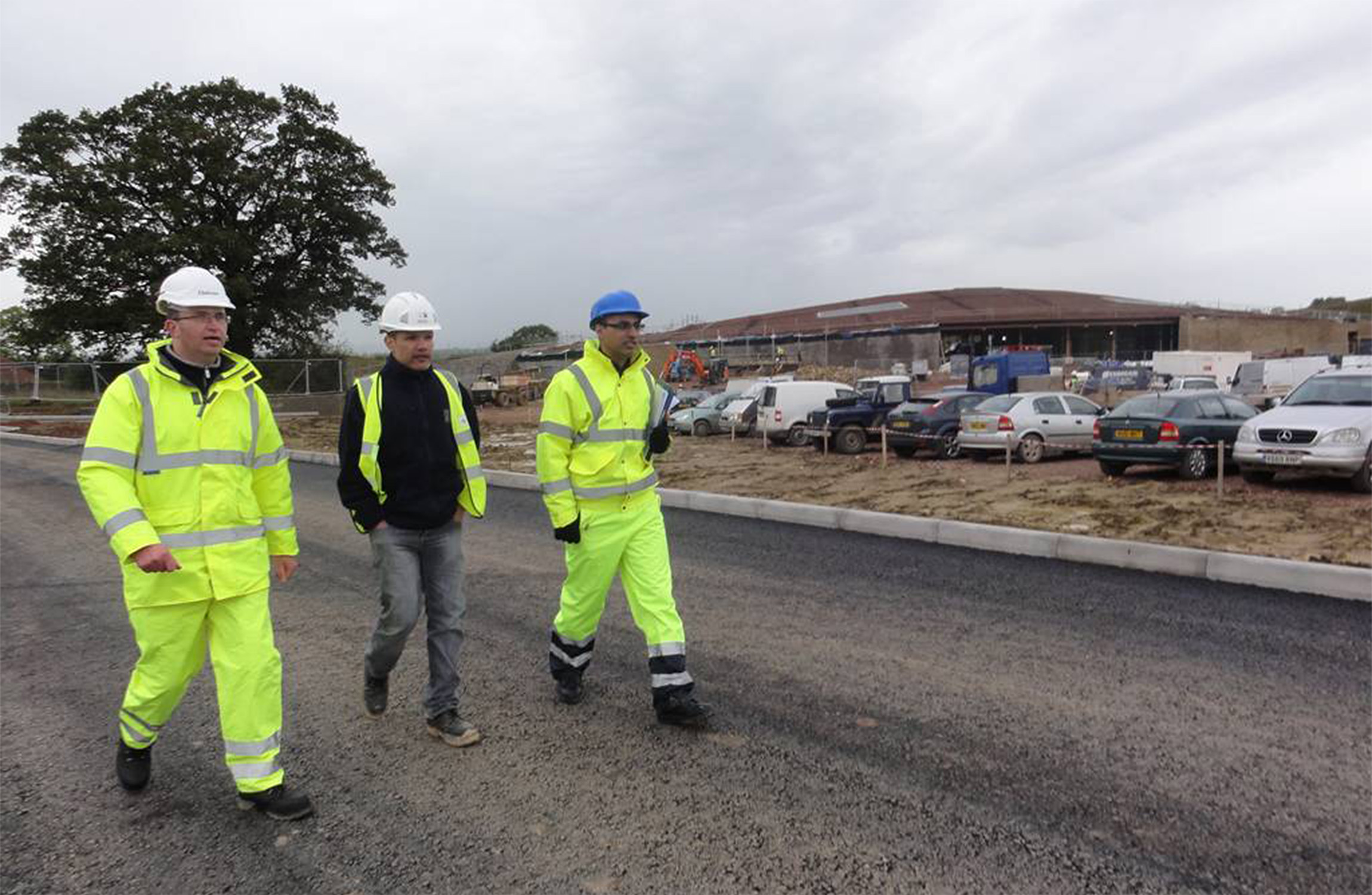 3 people walking on a road.